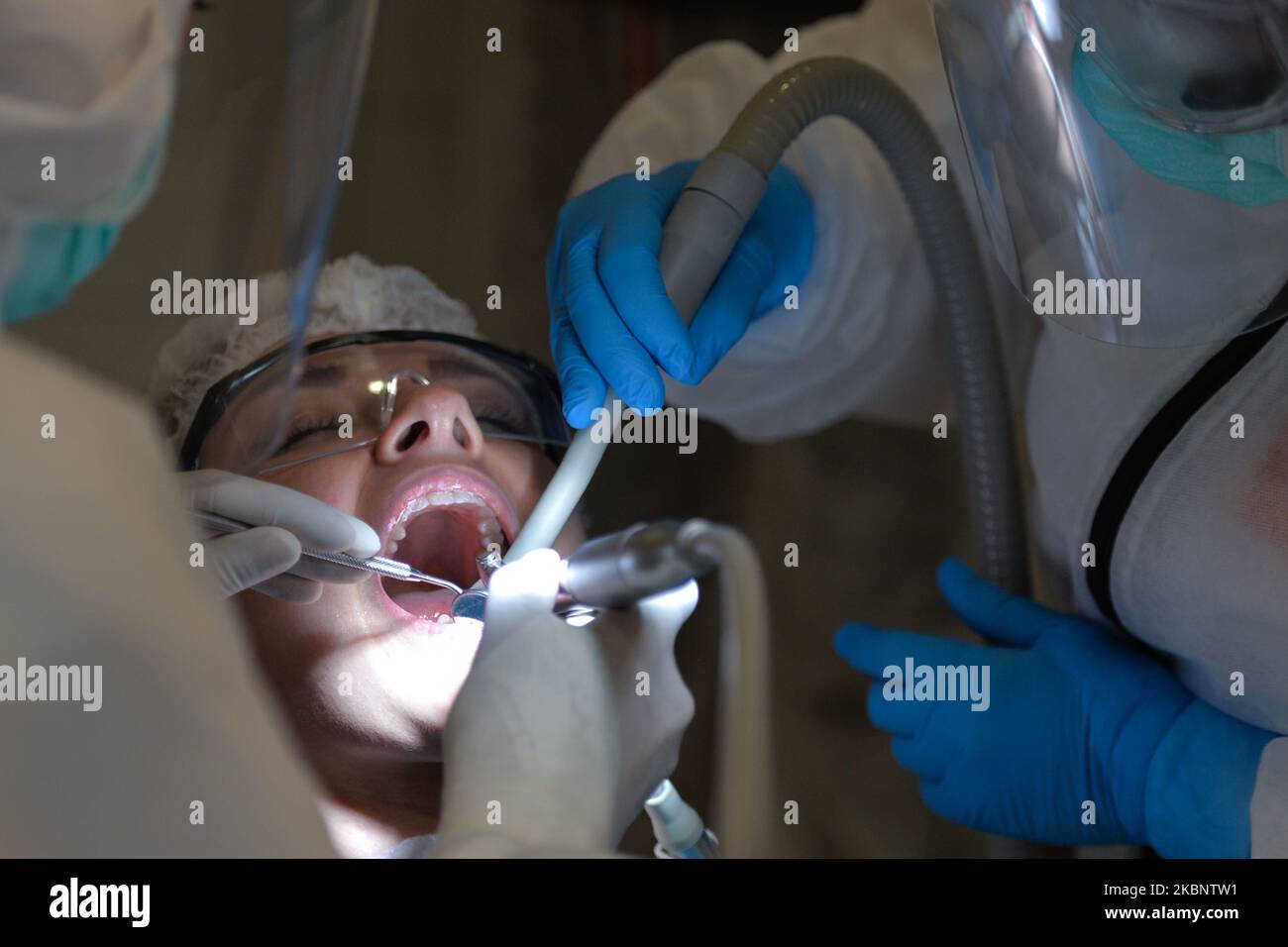 A dentist and her assistant wearing PPE attend to a patient at Dentima