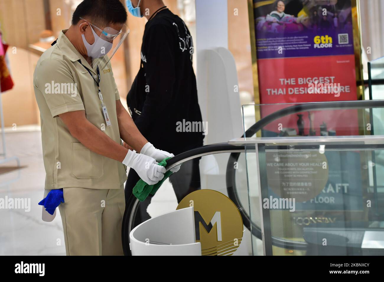 A cleaning staff wearing a face shield disinfecting handle of