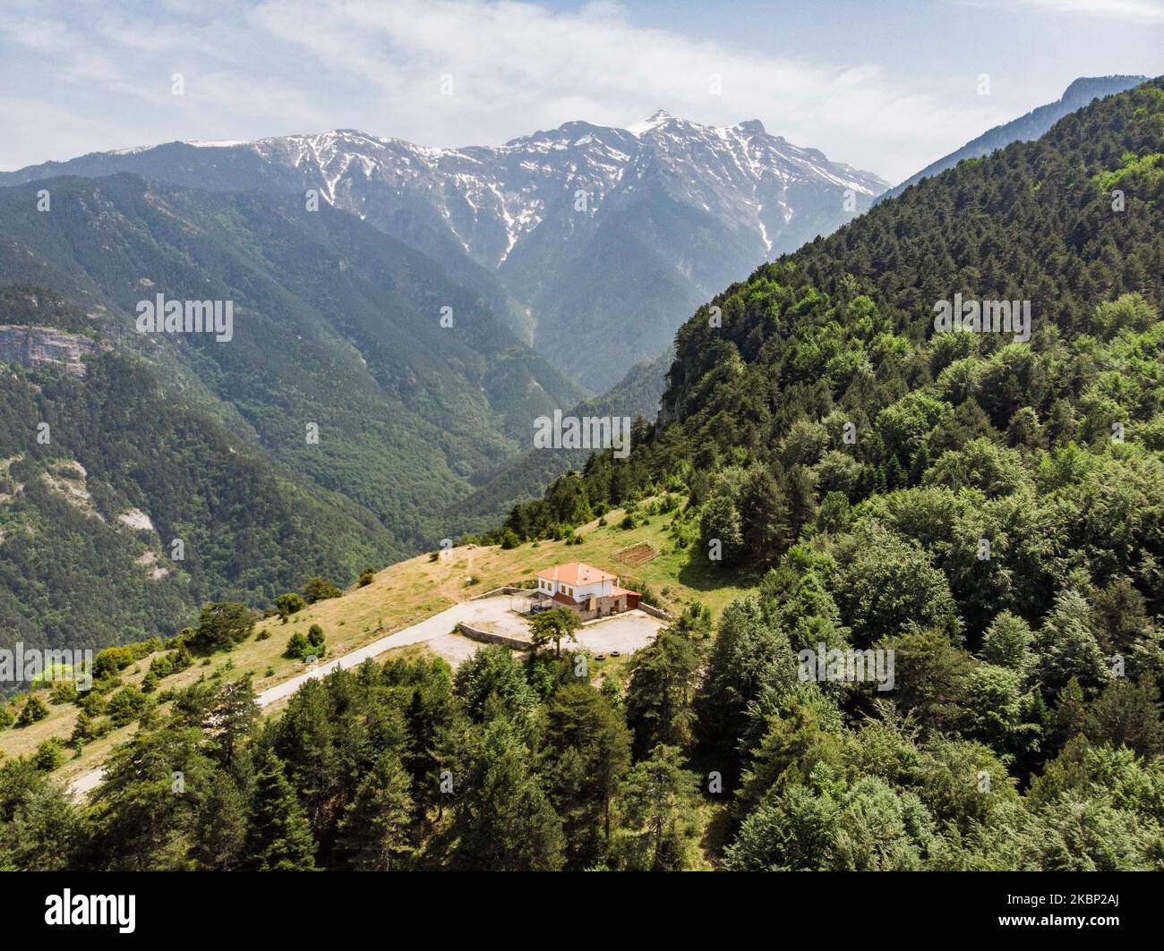 Aerial view of Mount Olympus, the highest mountain in Greece as seen from a drone with the steep hills, gorges, deep canyons, caves, thick forest and snow-covered peaks. The highest peak is Mytikasat 2918 meters and the mountain was notable in Greek Mythology as home of the gods. It is a National Park in Greece and a World Biosphere Reserve with rich biodiversity and flora. Olympus is an organized mountain with mount activities with many mountain refuges and many climbing and trekking routes for hikers or climbers. Near Olympus are the located the golden sand beaches of Pieria offering the com Stock Photo