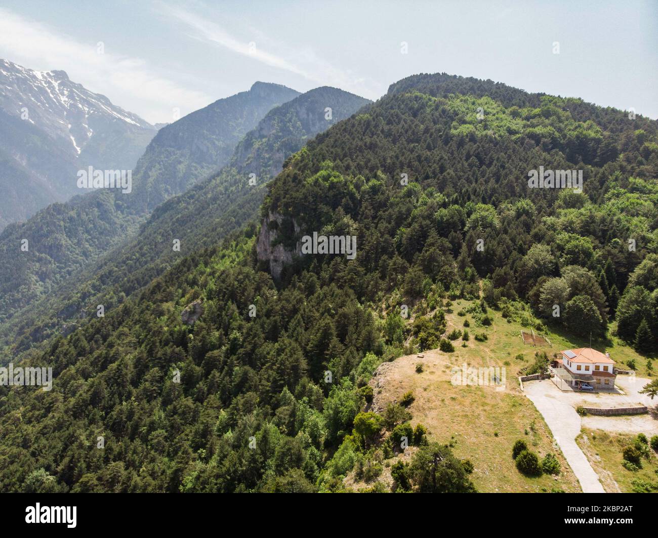 Aerial view of Mount Olympus, the highest mountain in Greece as seen from a drone with the steep hills, gorges, deep canyons, caves, thick forest and snow-covered peaks. The highest peak is Mytikasat 2918 meters and the mountain was notable in Greek Mythology as home of the gods. It is a National Park in Greece and a World Biosphere Reserve with rich biodiversity and flora. Olympus is an organized mountain with mount activities with many mountain refuges and many climbing and trekking routes for hikers or climbers. Near Olympus are the located the golden sand beaches of Pieria offering the com Stock Photo