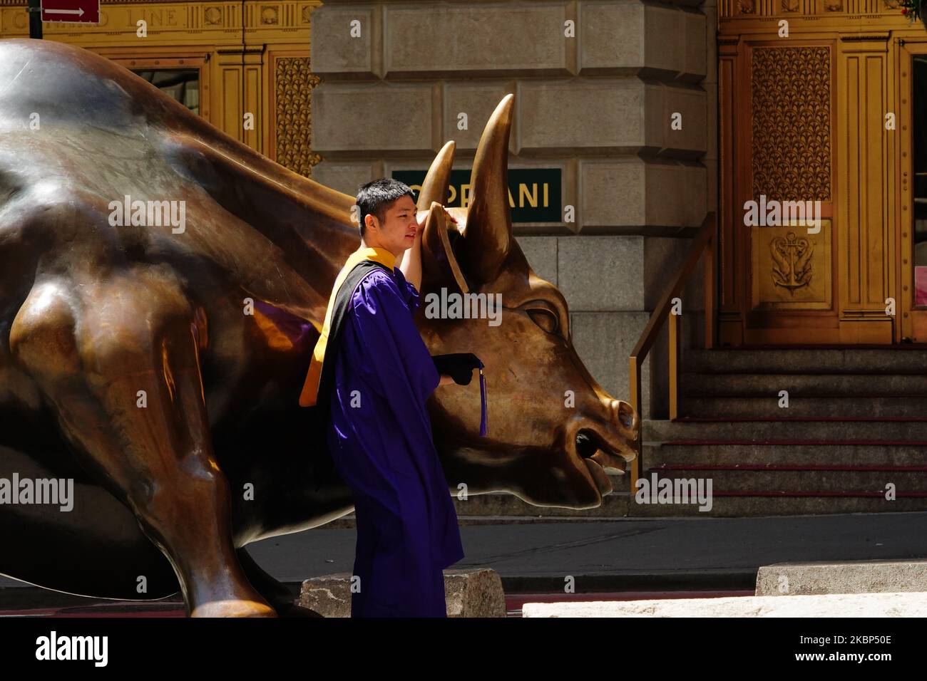 A view of new graduates taking photos at the Charging Bull during the coronavirus pandemic on May 20, 2020 in Bowling Green, New York City. COVID-19 has spread to most countries around the world, claiming over 316,000 lives with over 4.8 million infections reported. (Photo by John Nacion/NurPhoto) Stock Photo