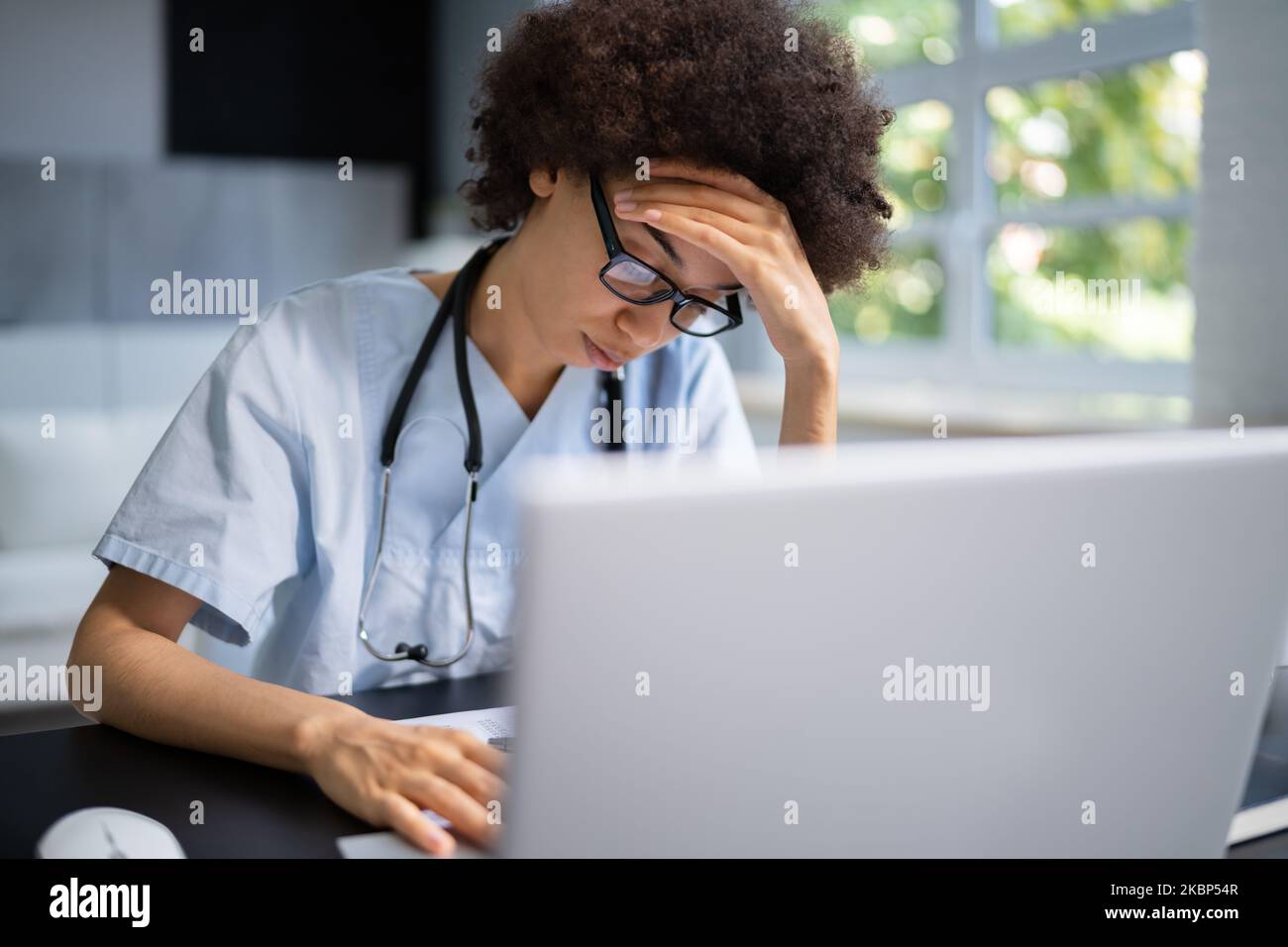 Frustrated Overworked Doctor In Hospital Looking At Computer Stock Photo