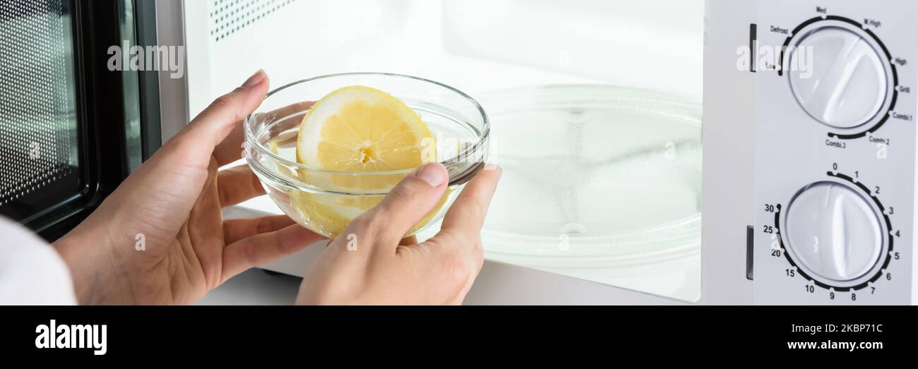 Woman Cleaning Microwave Oven With Lemon Fruit Stock Photo
