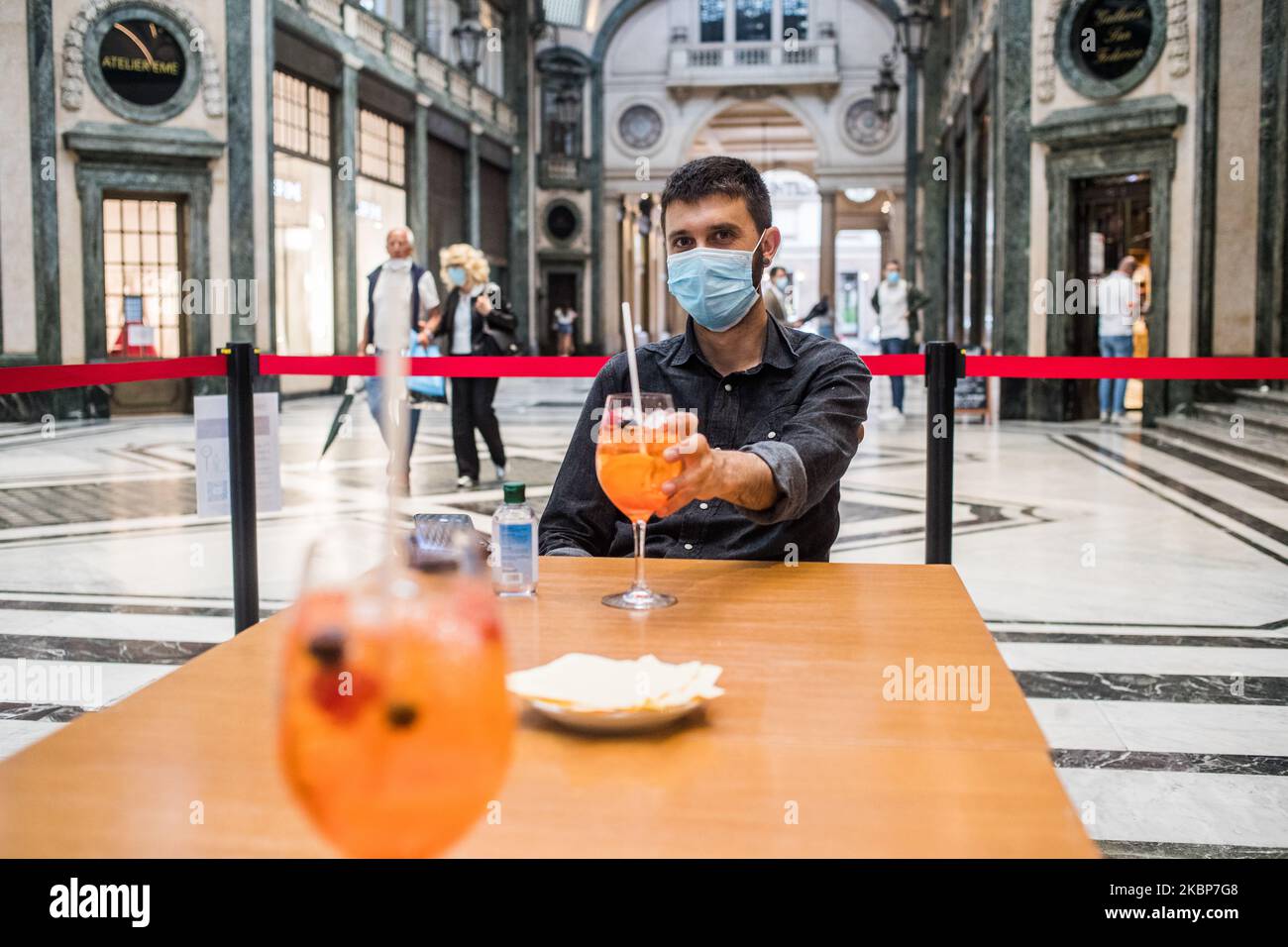 The photojournalist Stefano Guidi wearing a protective mask enjoys, at the end of a workday, a cocktail with colleagues in Galleria San Federico in Turin, Italy. On May 23, the Piedmont Region was able to reopen table seating at cafes and bars as long as people practice social distancing after more than two months of a nationwide lockdown meant to curb the spread of COVID-19. (Photo by Mauro Ujetto/NurPhoto) Stock Photo