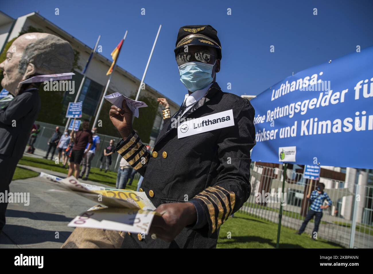 An activist dressed as an airline stewardess holds up oversized fake versions of Euro currency at a protest outside the Chancellery against the recent Lufthansa bailout during the coronavirus crisis on May 27, 2020 in Berlin, Germany. (Photo by Emmanuele Contini/NurPhoto) Stock Photo