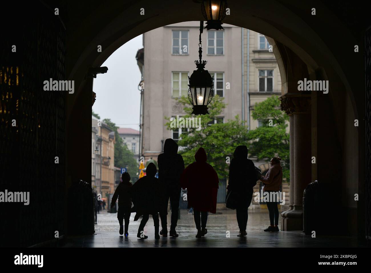 People walk in Krakow's Main Market Square during rainy weather. Rain has  returned again to Krakow area and is predicted to remain for at leat  another week. On Sunday, May 31, 2020,