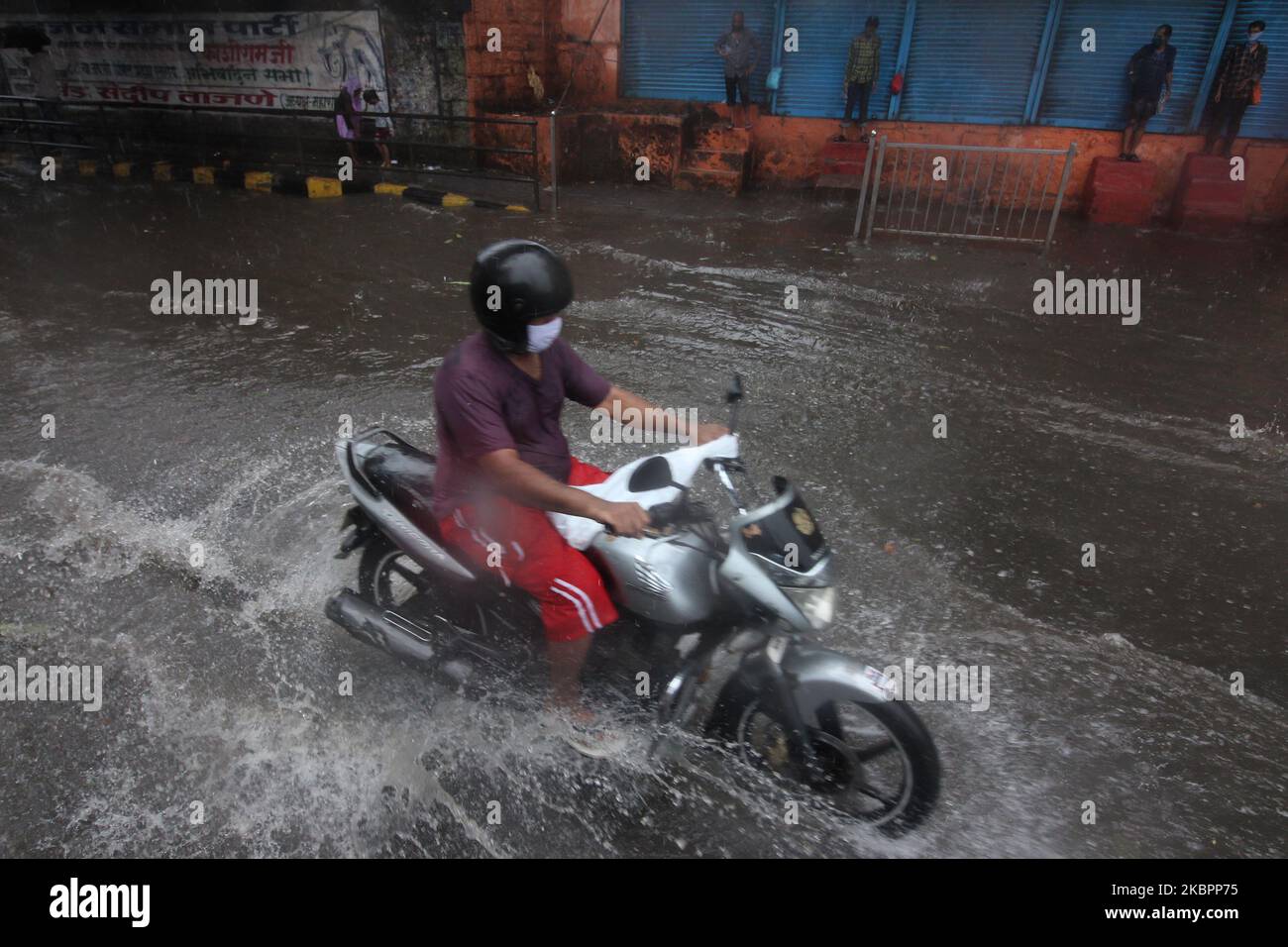 A man rides a motorcycle through flood waters during heavy rains in