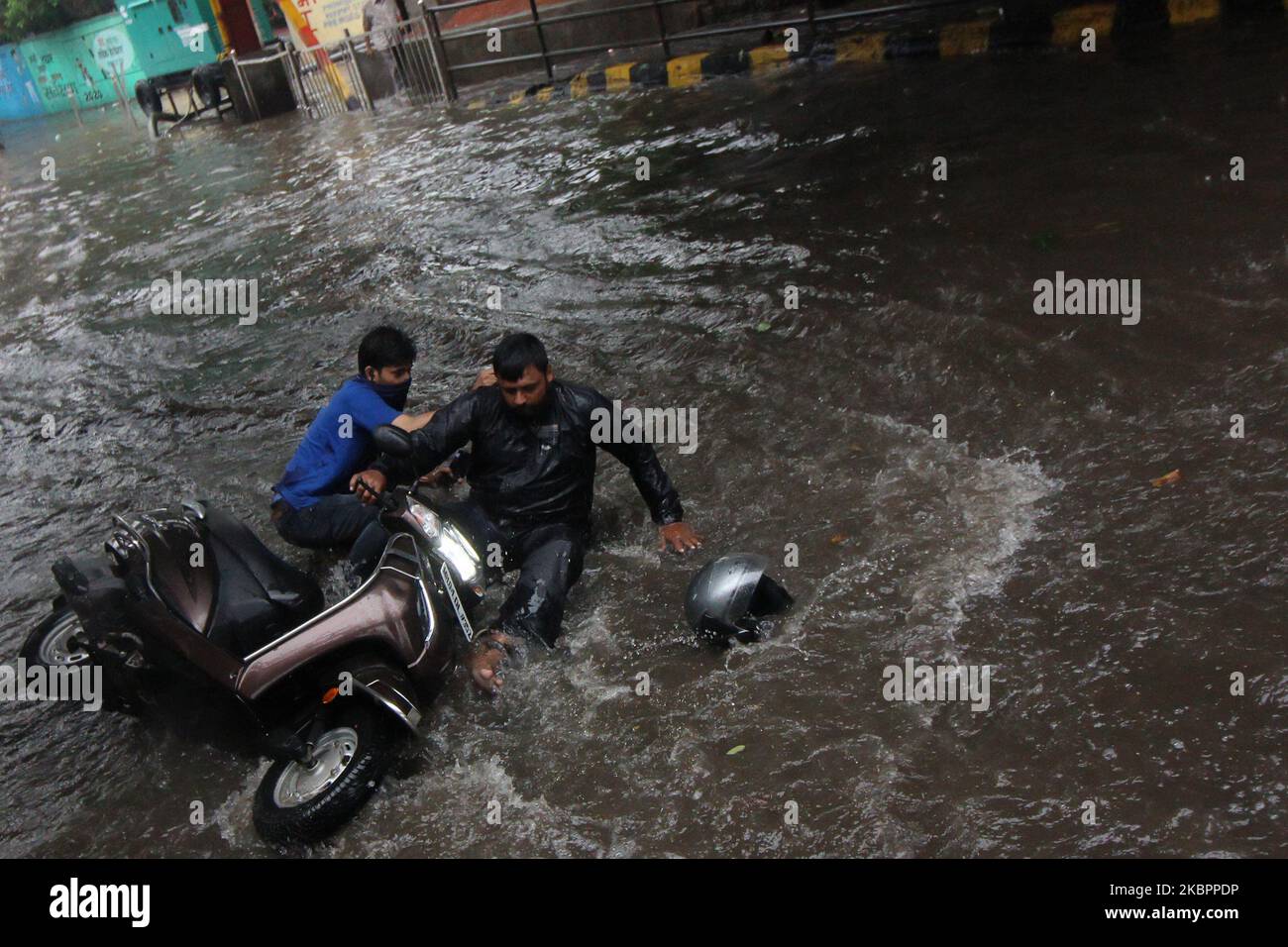 A motorcycle rider loses control of his bike on a flooded street after
