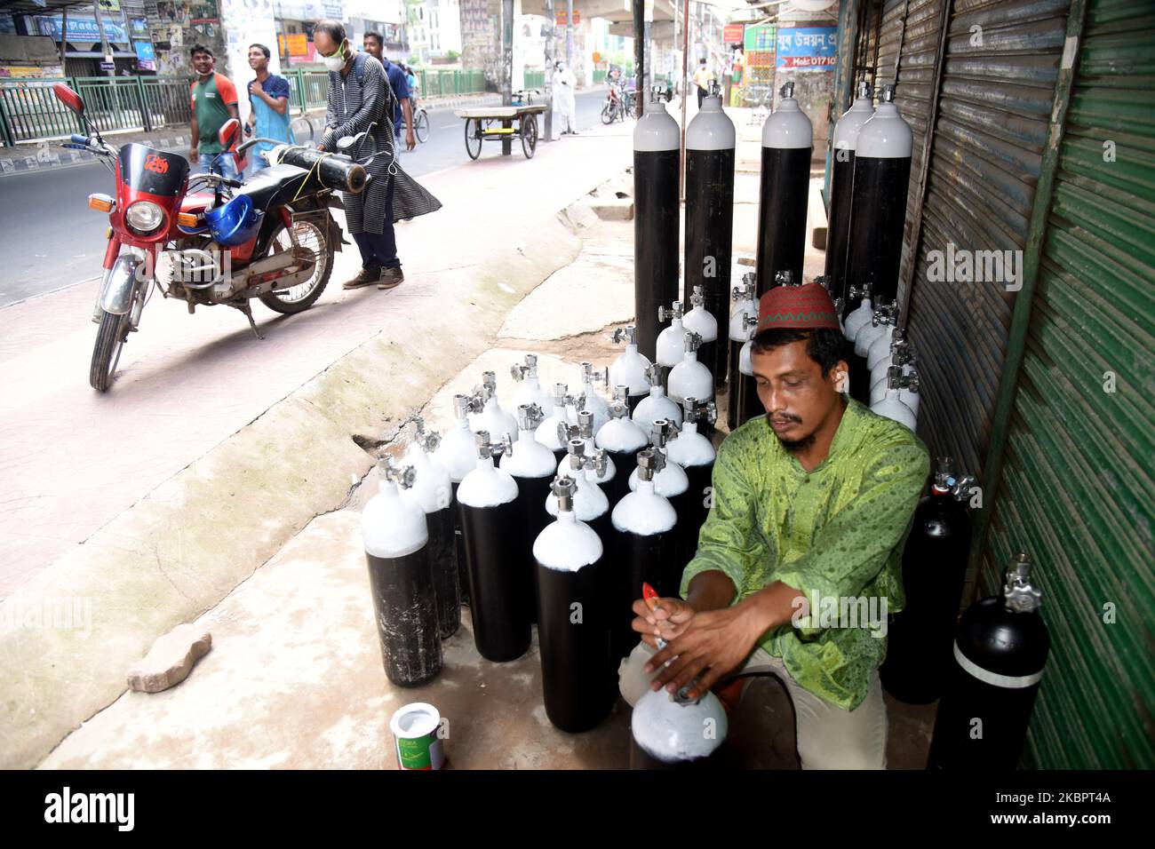 Worker cleaning an oxygen cylinder at a store as cylinders demand rise ...