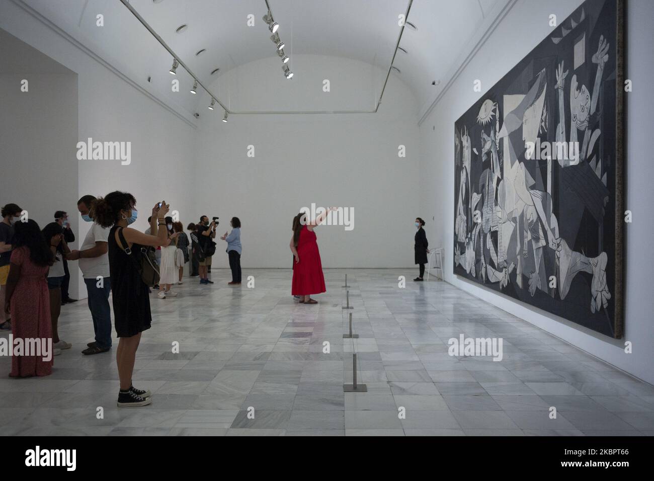 (EDITORIAL NEWS USE ONLY - STRICTLY NO COMMERCIAL OR MERCHANDISING USAGE) People look at Guernica by Pablo Picasso during the partial reopening of the Reina Sofia Museum, after its closure in March due to the Covid-19 pandemic, on June 06, 2020 in Madrid, Spain. A maximum of 30 people (30%) at a time are now allowed to view Picasso's iconic anti-war painting depicting the 1937 bombing of the Basque town of Guernica during the Spanish civil war. (Photo by Oscar Gonzalez/NurPhoto) Stock Photo
