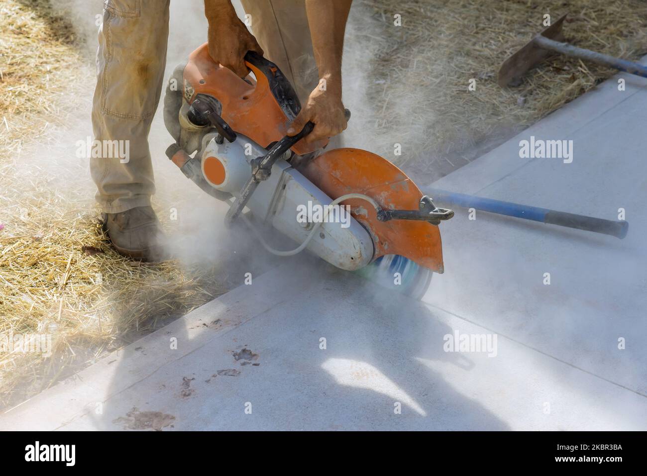 Construction worker uses diamond blade saw to cut concrete sidewalk Stock Photo