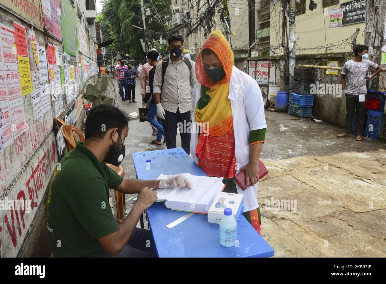 Residents wearing Facemask get out in an emergency after registration from the government imposed coronavirus red zone with maximum infection risk at East Rajabazar in Dhaka, Bangladesh.on June 14, 2020.The authorities put East Rajabazar in Dhaka on total lockdown from June 10, allowing no one to leave or enter the area, after it was declared coronavirus red zone with maximum infection risk. (Photo by Mamunur Rashid/NurPhoto) Stock Photo
