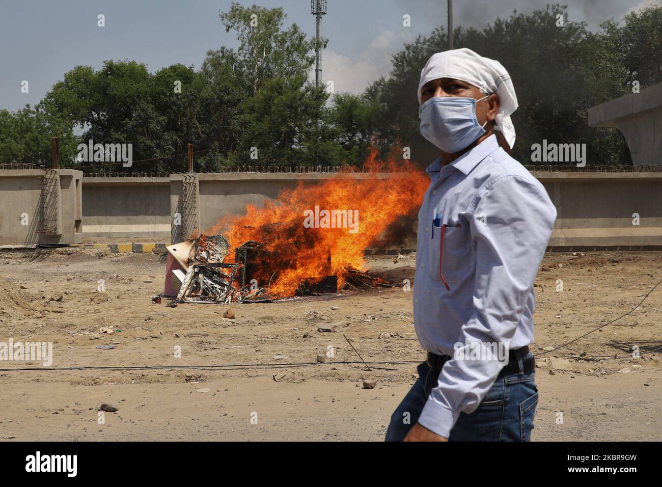 A man wearing a mask walks past the burned chinese products during a protest against Chinese President Xi Jinping in Gurugram on the outskirts of New Delhi, India on 17 June 2020. Seventeen Indian Army soldiers have succumbed to their injuries suffered during the India-China face-off at Galwan Valley in Eastern Ladakh, taking the casualty figure on the Indian side to 20. (Photo by Nasir Kachroo/NurPhoto) Stock Photo