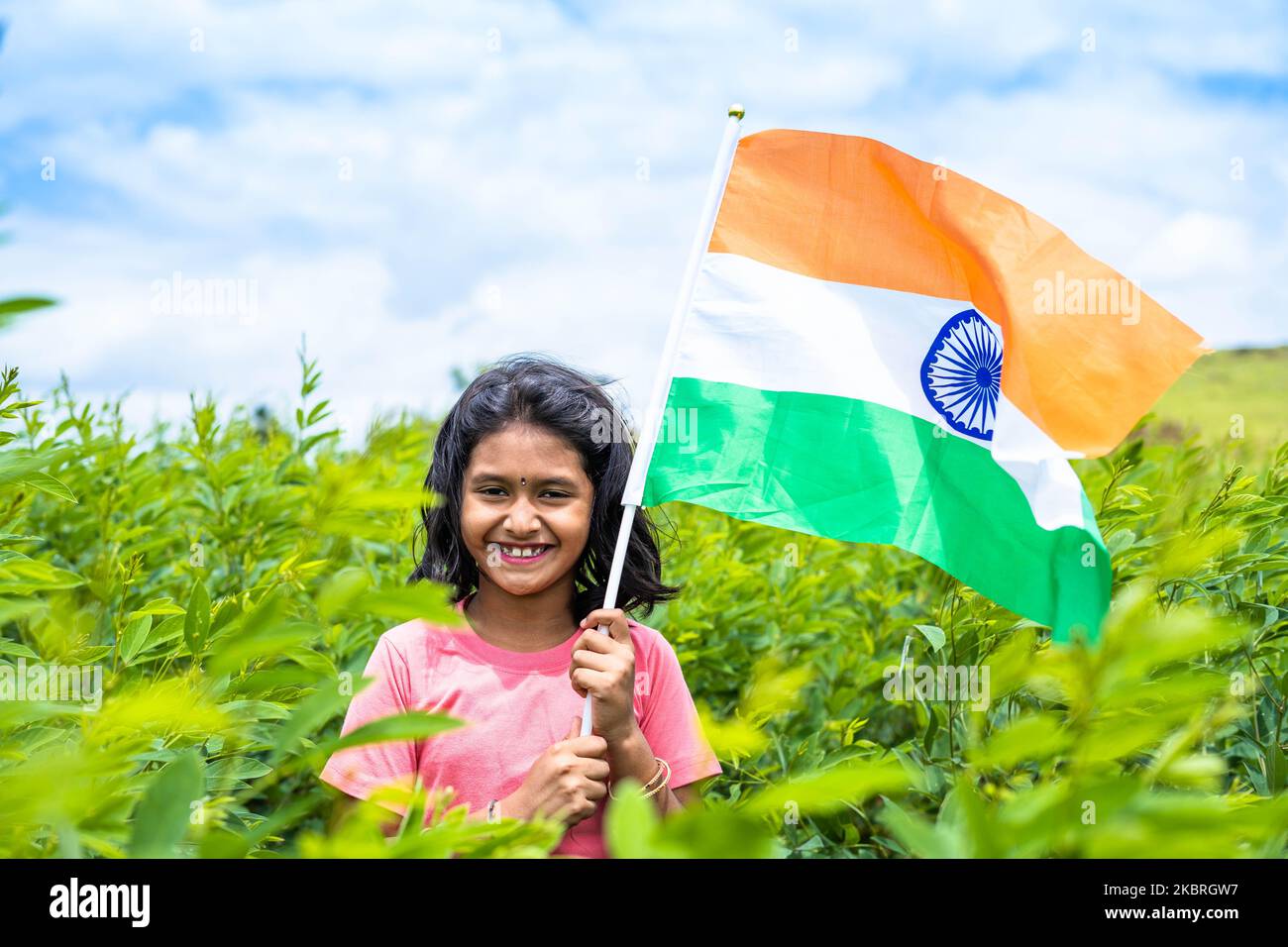 Happy smiling teenager girl holding indian flag at farmland - concept of freedom, patriotism and education Stock Photo