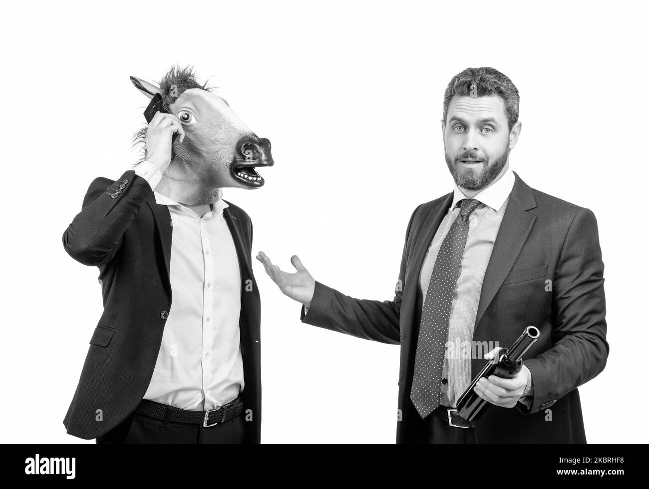 Drunk businessman show at hardworking man in horse head talking on phone on party, workaholic Stock Photo