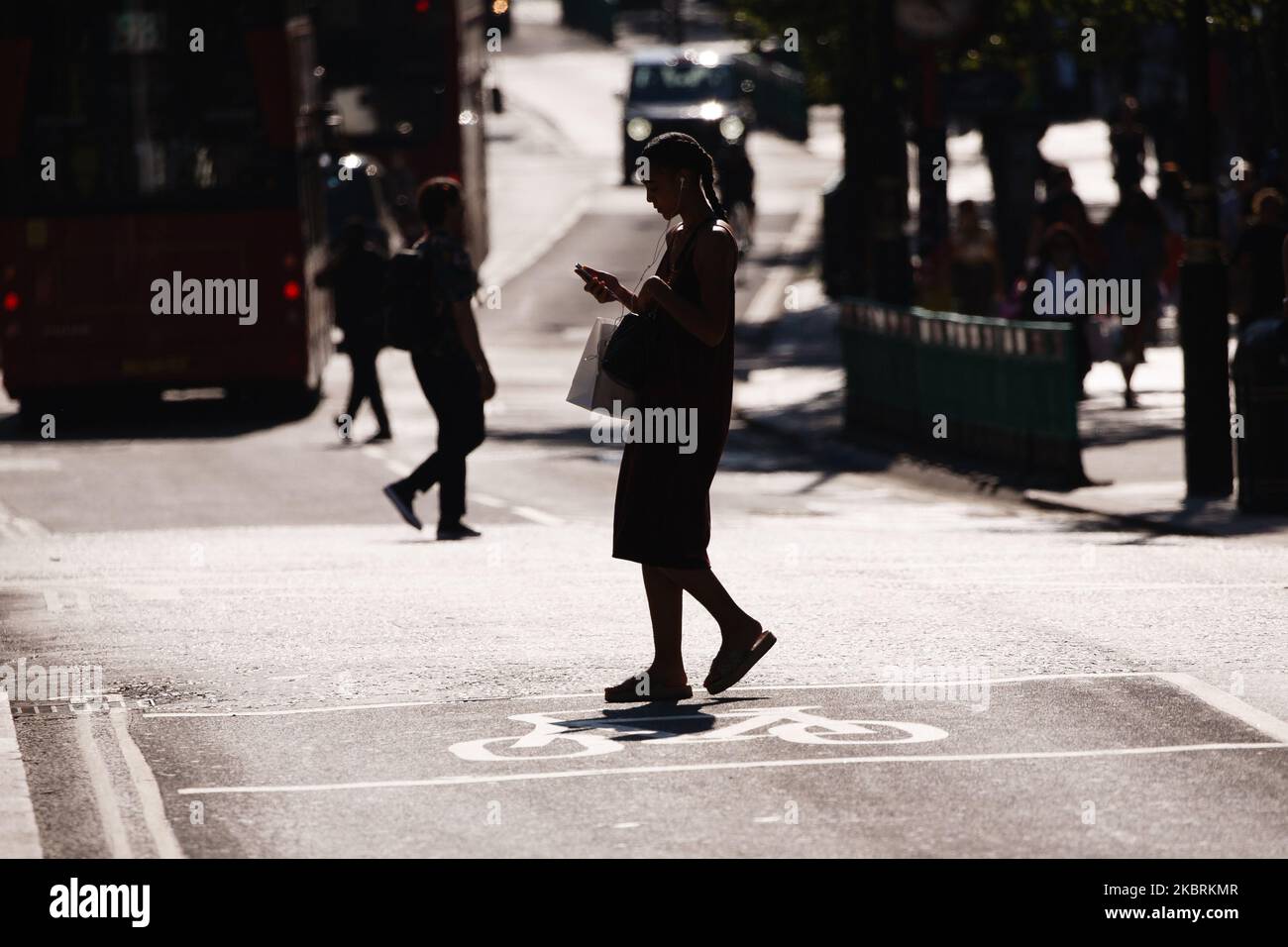 A shopper crosses Oxford Street in heatwave conditions in London, England, on June 25, 2020. Temperatures rose to 33C in parts of London today, in what has been one of the UK's hottest days of the year so far. Central London was nonetheless busy with shoppers this afternoon as the retail sector mounts its comeback after coronavirus lockdown restrictions on non-essential shops were eased at the beginning of last week. Among retailers, confidence is reportedly low that recovery will be swift, however, with a survey from the Confederation of British Industry (CBI) today revealing fears of reduced Stock Photo