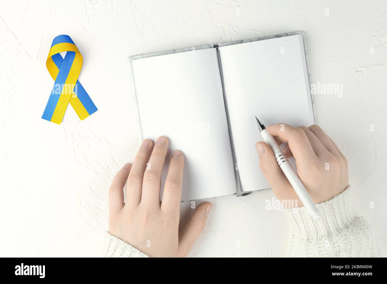 hands with blank notepad and ukraine ribbon Stock Photo