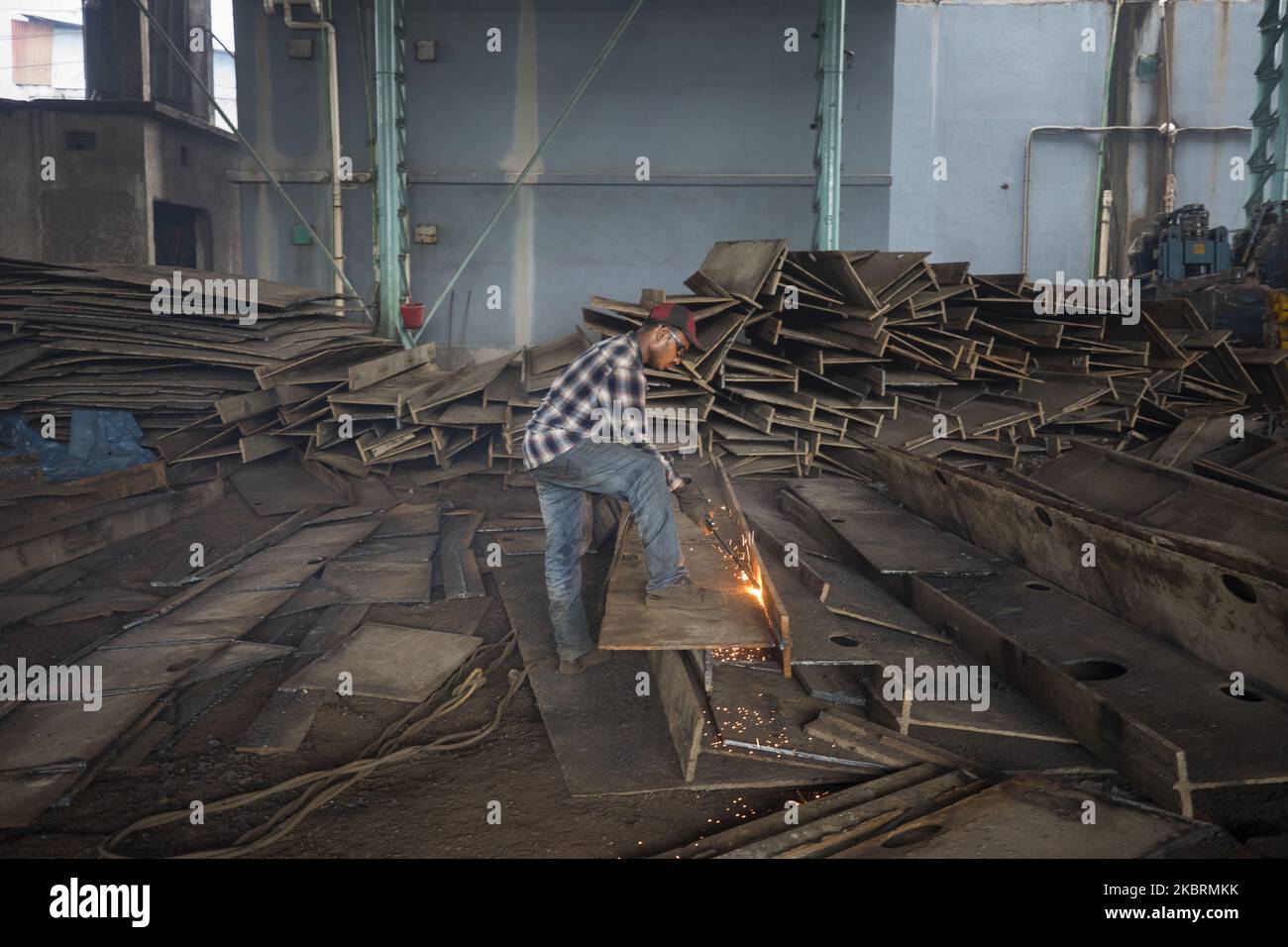 A Bangladeshi labourer welds in the steel re-rolling mills work without proper safety gear or tools in Narayanganj, Bangladesh on June 26, 2020. In these mills iron is forged in 1200 + to 1300+ Celsius. In such a heated place the soles of their shoes are likely to be burnt off with one careless step. (Photo by Ahmed Salahuddin/NurPhoto) Stock Photo