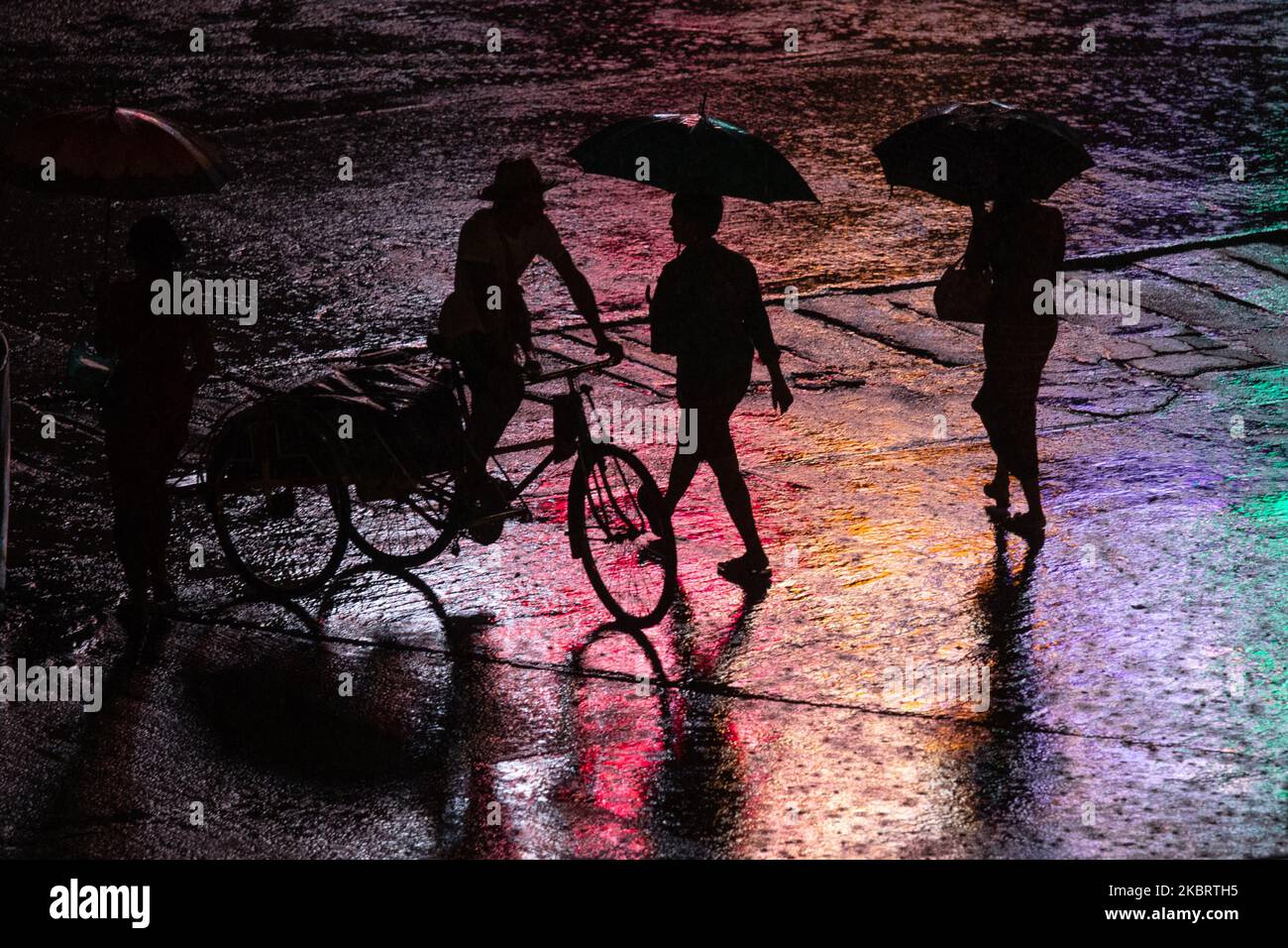 A trishaw driver and people cross the road during a heavy rainfall in Yangon on June 29, 2020. (Photo by Shwe Paw Mya Tin/NurPhoto) Stock Photo