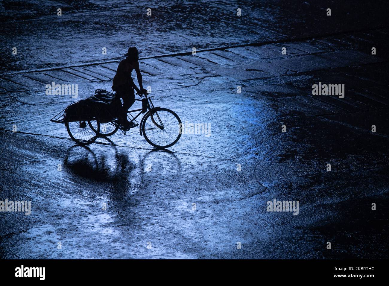 A trishaw driver crosses the road during a heavy rainfall in Yangon on June 29, 2020. (Photo by Shwe Paw Mya Tin/NurPhoto) Stock Photo