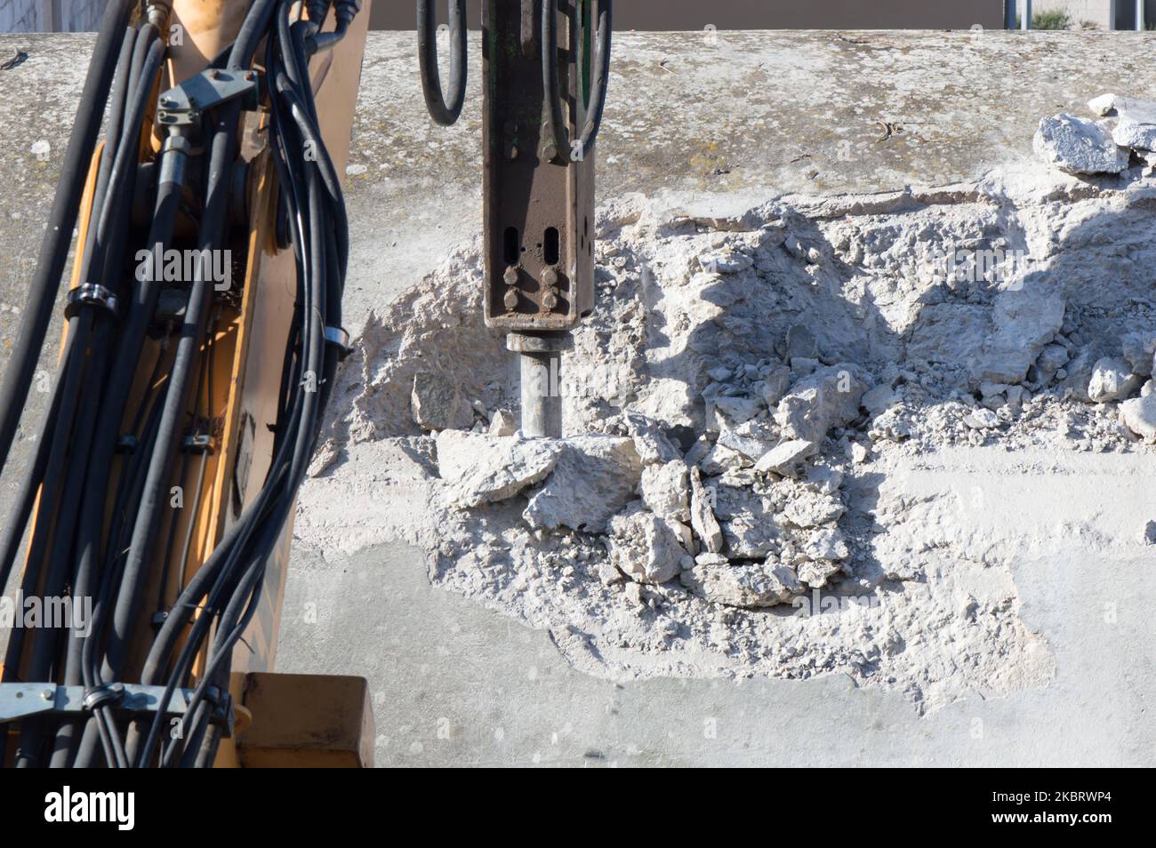 Demolishing hard concrete structure with the breaker, percussion hammer mounted on the excavator
