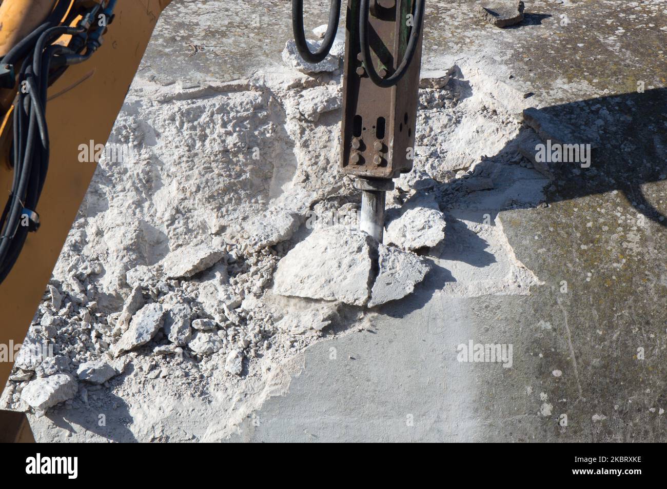 Demolishing hard concrete structure with the breaker, percussion hammer mounted on the excavator