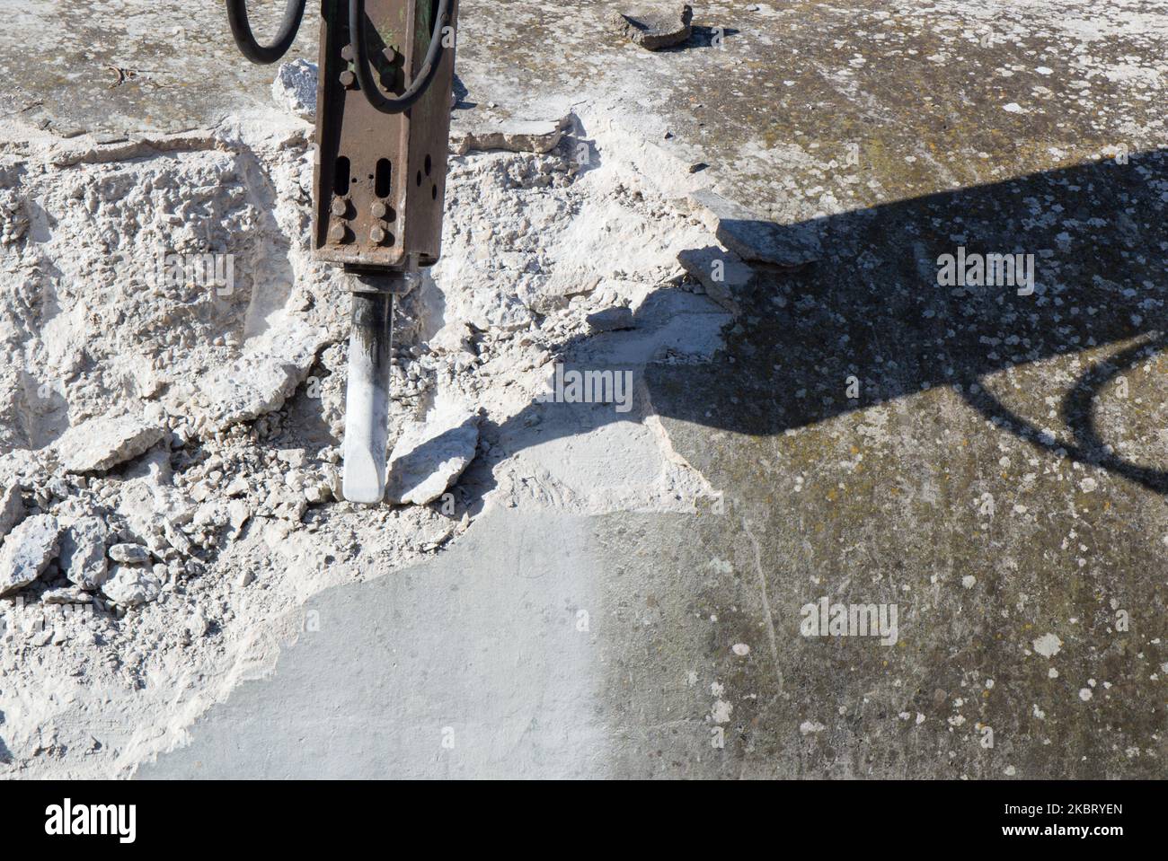 Demolishing hard concrete structure with the breaker, percussion hammer mounted on the excavator
