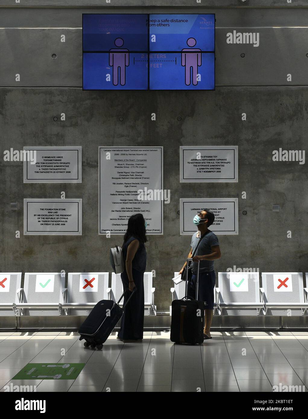 A man and a woman in protective masks while waiting for a flight at the