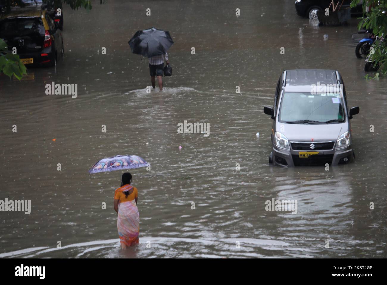 People wade through a flooded street during heavy rains in Mumbai ...