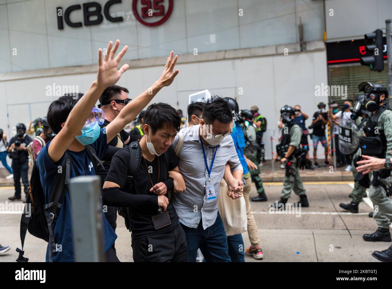 District councilors blinded by pepper spray hold hands as they move