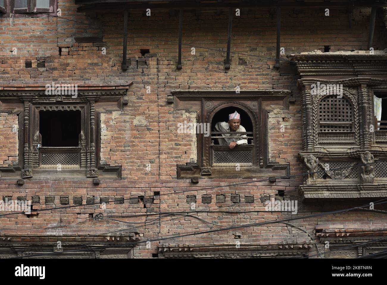 An oldman glancing from a traditional window at Kirtipur, Kathmandu Nepal on July 16, 2020. (Photo by Narayan Maharjan/NurPhoto) Stock Photo