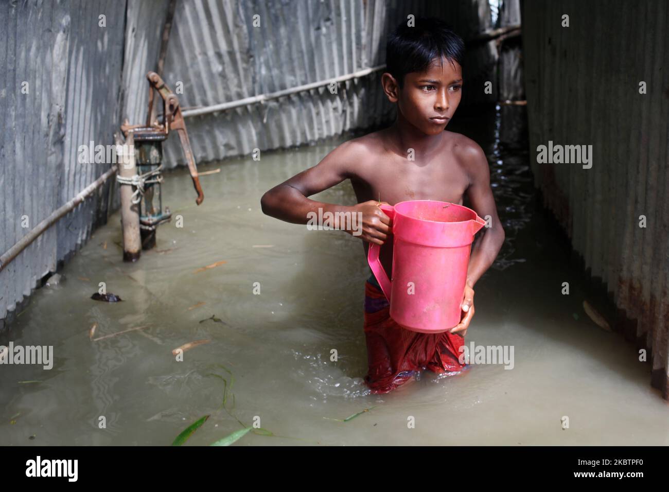 A children carry drinking water as he walks through flood water in