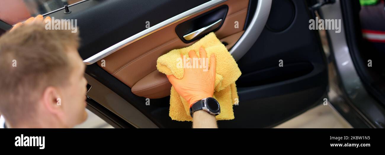 Man cleans car door handle with cloth and car detailing. Car wash