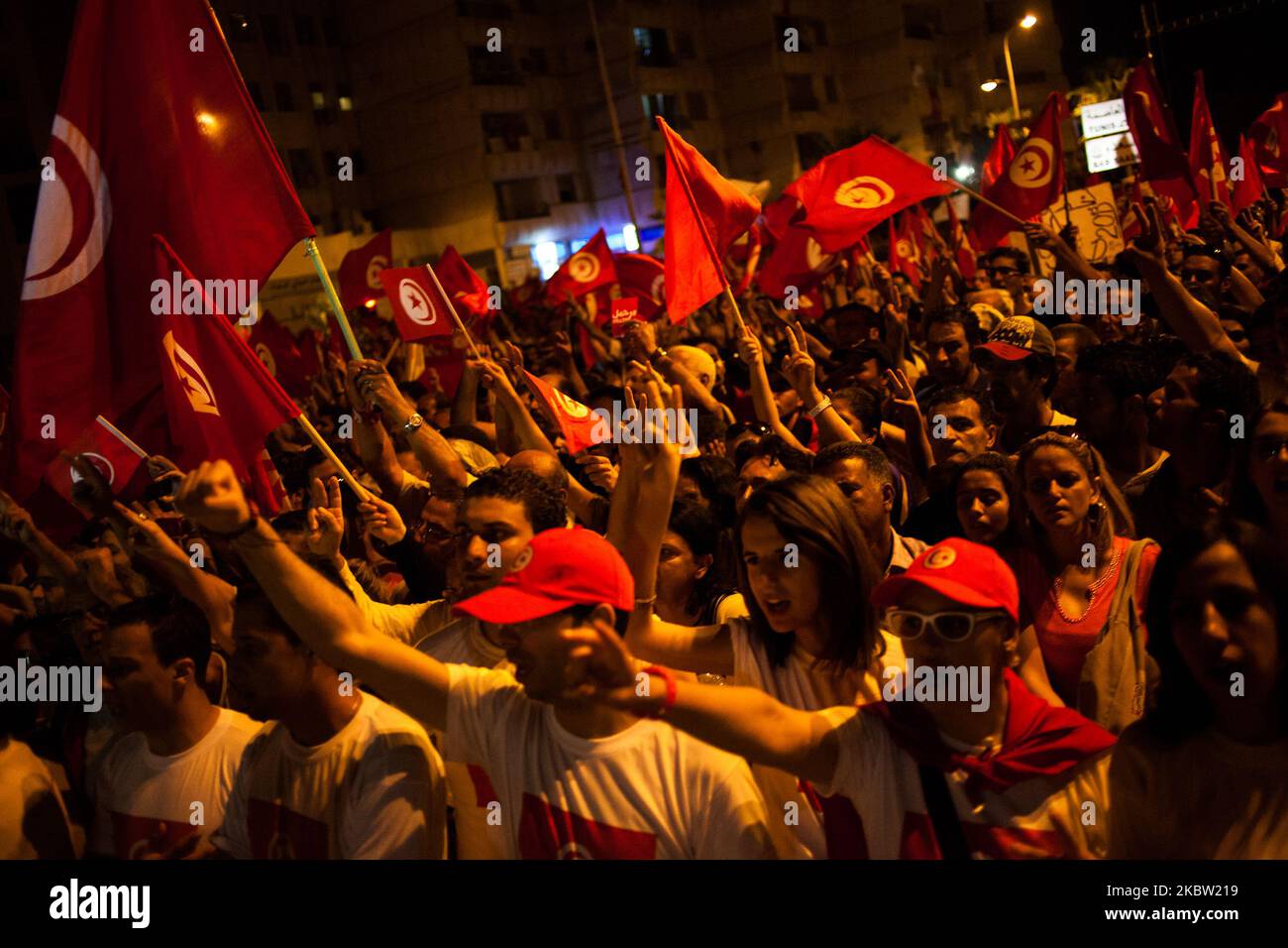 People wave a tunisien flag during a march outside the National Assembly at the bardo to mark the 40th day since the assassination of opposition politician Mohamed Brahmi. Brahmi was shot dead by unknown gunmen outside his home. On 7 September 2013, in Tunis, Tunisia. (Photo by Emeric Fohlen/NurPhoto) Stock Photo