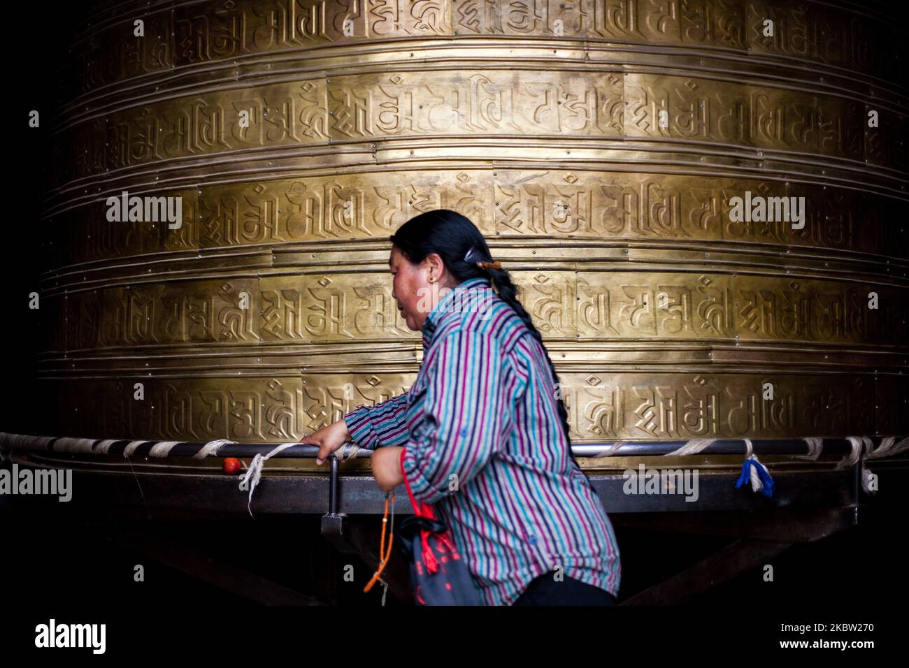 Xining, China, the 4 July 2011. A Tibetan woman pray in a temple by rolling prayer wheel. (Photo by Emeric Fohlen/NurPhoto) Stock Photo
