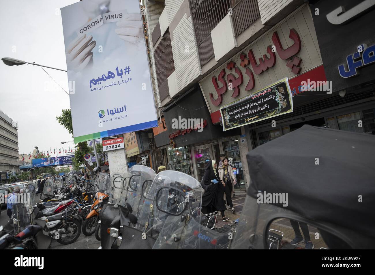 Two Iranian women who not to wear protective face mask walk past a billboard that is hanged on a street-side in Tehran’s business district following the new coronavirus disease (COVID-19) outbreak in Iran, April 25, 2020. (Photo by Morteza Nikoubazl/NurPhoto) Stock Photo