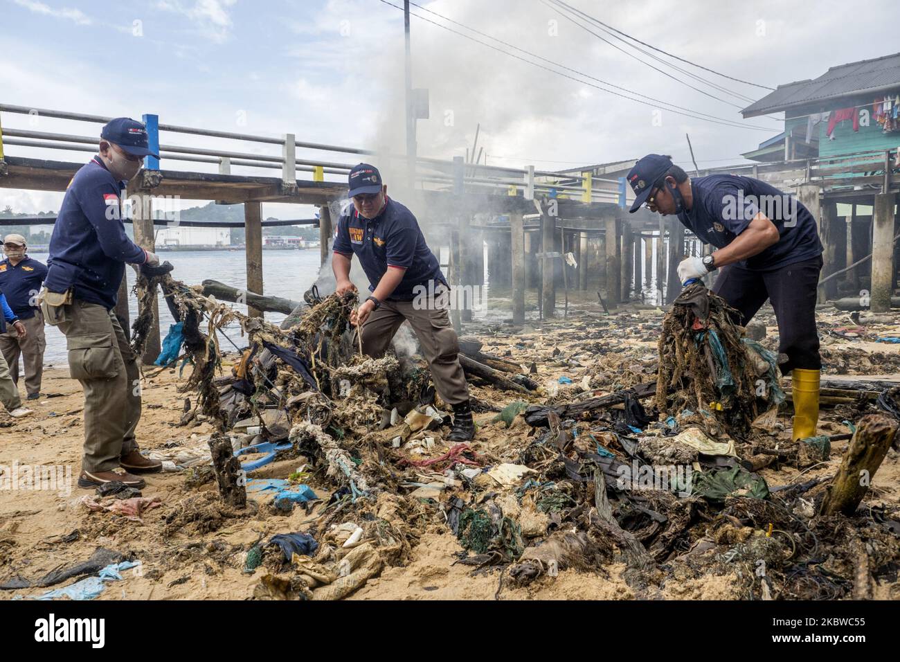 Residents together with cleaning staff collect rubbish, at the edge of ...