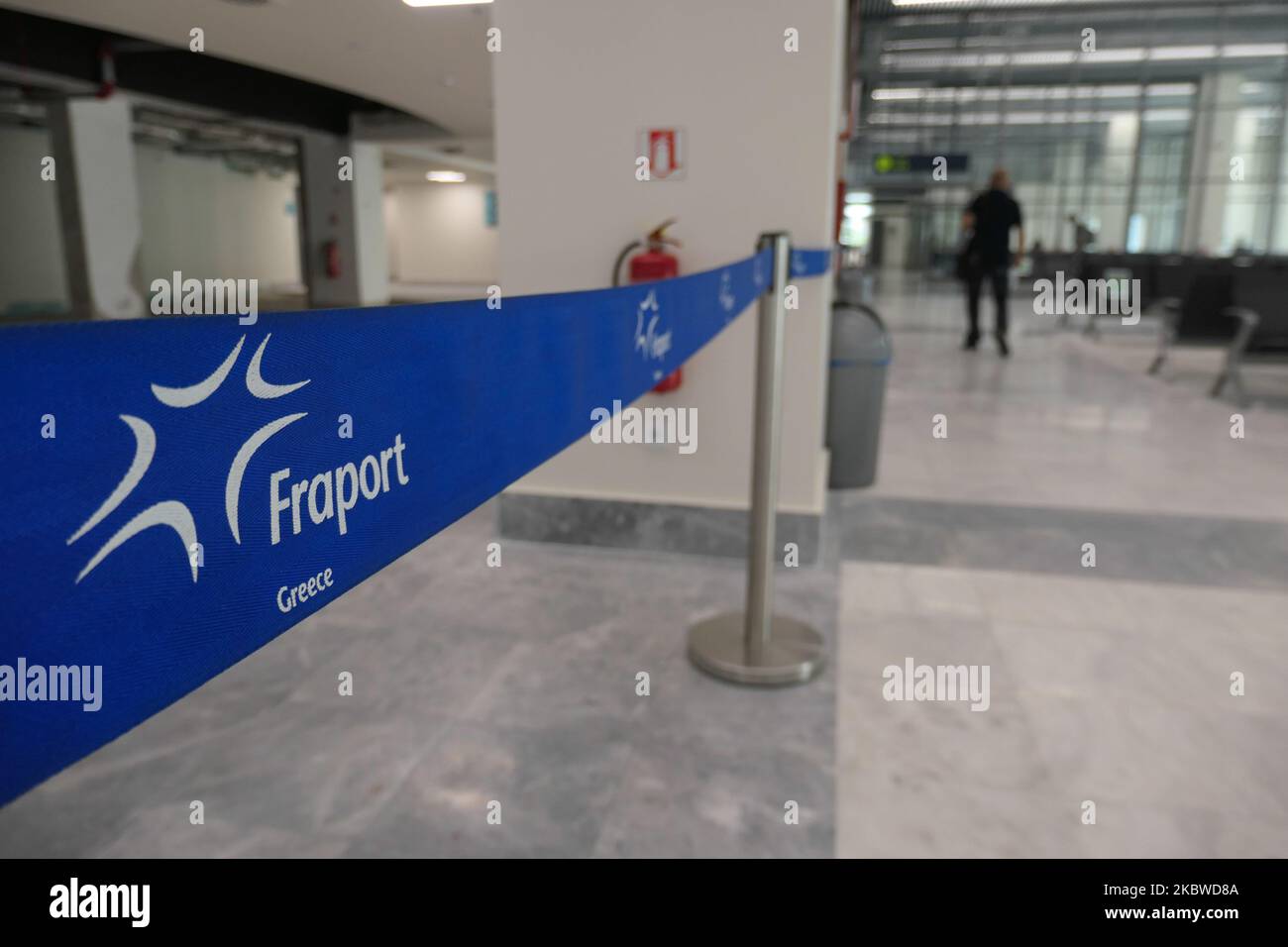 Fraport sign in a ribbon inside the airport. Flying from Mykonos International Airport JMK LGMK in Greece. Passengers with facemasks and protective measures as gloves, hand sanitizer, blocking seats, social distancing signs etc because of the Coronavirus Covid-19 Pandemic safety measures, as seen at the check-in counters, main departure terminal, at the gates and walking towards the aircraft, an Olympic Air turboprop airplane Bombardier DHC-8-400 with registration SX-OBA. The airport is owned by the Greek Government but is operated by Fraport Greece since 11 April 2017 after the privatization  Stock Photo