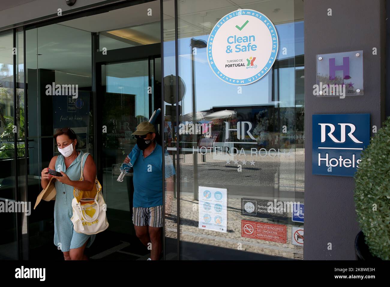 Tourists wearing facial masks leave a Hotel with the Clean and Safe stamp in Portimao, Algarve region, Portugal on July 29, 2020. Considering the widespread concern in the resumption of economic and social activity, Turismo de Portugal created a Clean and Safe stamp of approval to distinguish tourist activities which are compliant with hygiene and cleaning requirements for the prevention and control of COVID-19 and other possible infections. (Photo by Pedro FiÃºza/NurPhoto) Stock Photo