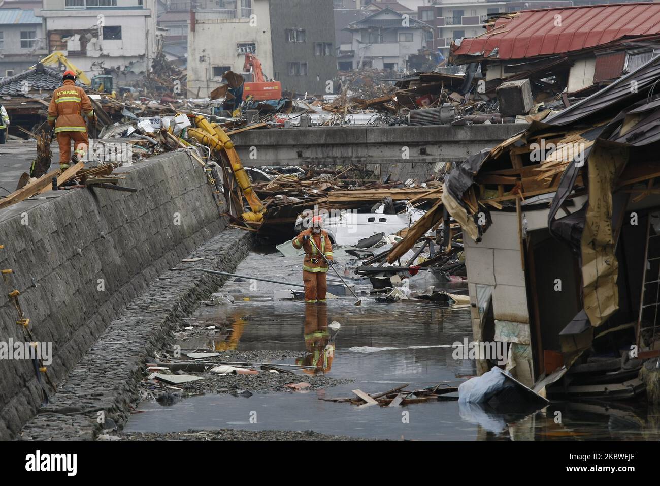March 21, 2011-Ofunato, Japan-Rescue team searching burial body on debris and mud covered at Tsunami hit Destroyed Industrial Area in Ofunato on March 21, 2011, Japan. On 11 March 2011, an earthquake hit Japan with a magnitude of 9.0, the biggest in the nation's recorded history and one of the five most powerful recorded ever around the world. Within an hour of the earthquake, towns which lined the shore were flattened by a massive tsunami, caused by the energy released by the earthquake. With waves of up to four or five metres high, they crashed through civilians homes, towns and fields. (Pho Stock Photo