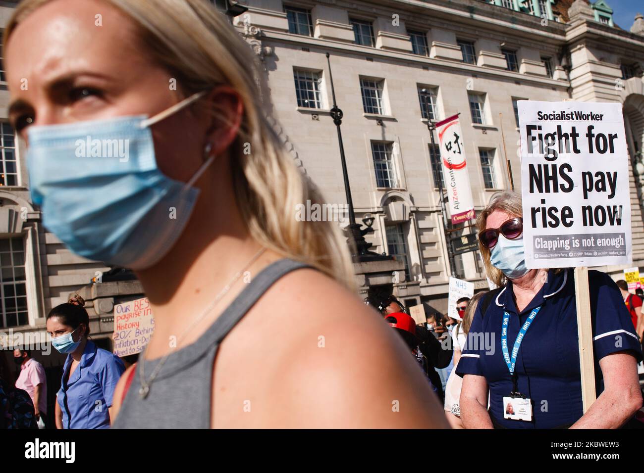 National Health Service (NHS) staff, protesting their exclusion from a recently-announced public sector pay rise, demonstrate outside St Thomas' Hospital in London, England, on July 29, 2020. Around 900,000 public sector workers across the UK are set to receive above-inflation pay rises this year as a gesture of thanks from the Treasury for their efforts during the coronavirus pandemic. Within the NHS, doctors and dentists will benefit from the rises, but nurses and other frontline staff have been excluded owing to a three-year pay deal they negotiated in 2018. Nursing activists say that so-ca Stock Photo