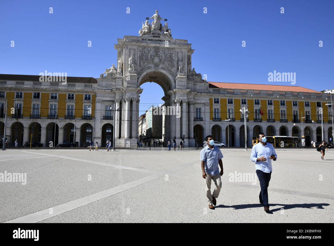 Two persons wearing protective masks walk in Praça de Comércio, Lisbon. July 30th, 2020. With the arrival of summer Portugal reopens its doors to tourism. Flights from outside the European Union will now be allowed, but passengers will have to take the Covid-19 test. The measure was announced this Thursday by the Minister of Internal Administration Eduardo Cabrita. According to the bulletin of the Health General Direction, since the beginning of the pandemic, 50,868 cases of infection and 1,727 deaths have been confirmed.The region of Lisbon and Vale do Tejo is where the largest outbreak of co Stock Photo