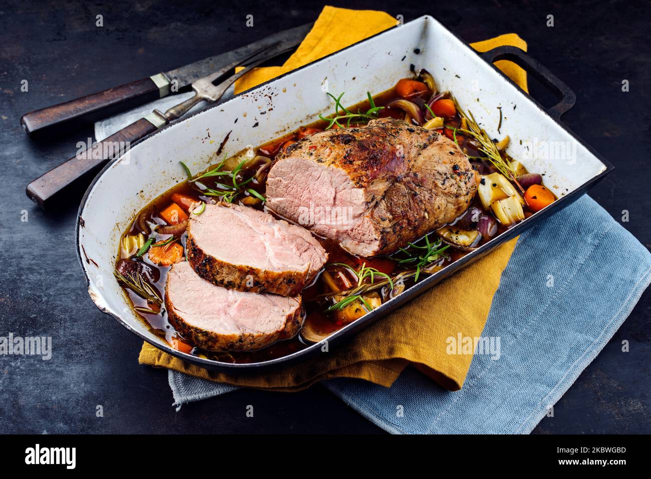 Traditional German pork roast served with vegetable and herbs in dark