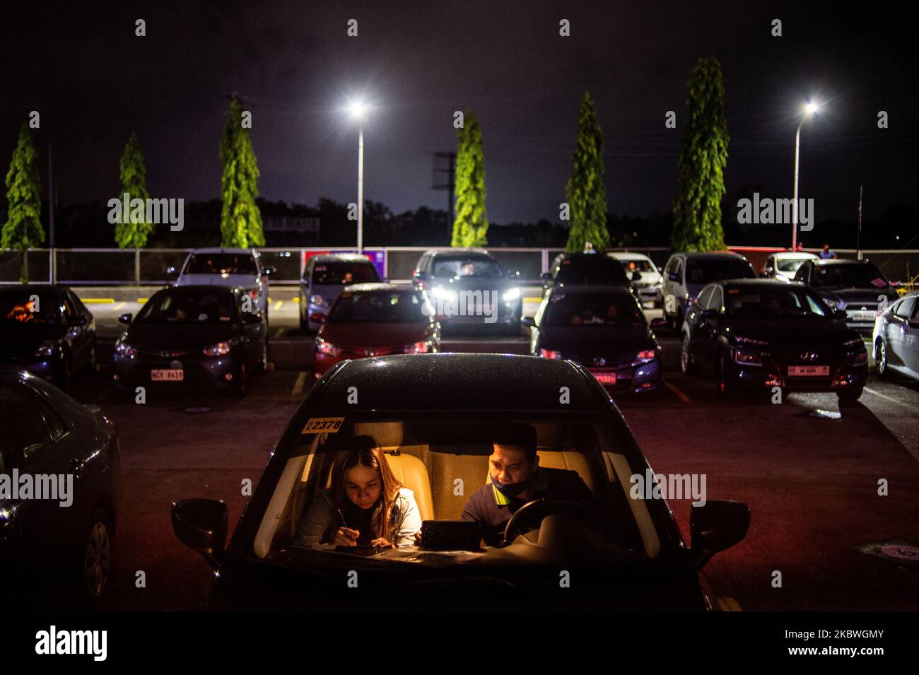 A couple fill out a contact tracing form while inside their car before a movie starts at a drive-in cinema in the province of Pampanga in Philippines on July 31, 2020. The drive-in cinema, with the capacity of about 90 cars, is the first to open in the country.(Photo by Lisa Marie David/NurPhoto) Stock Photo