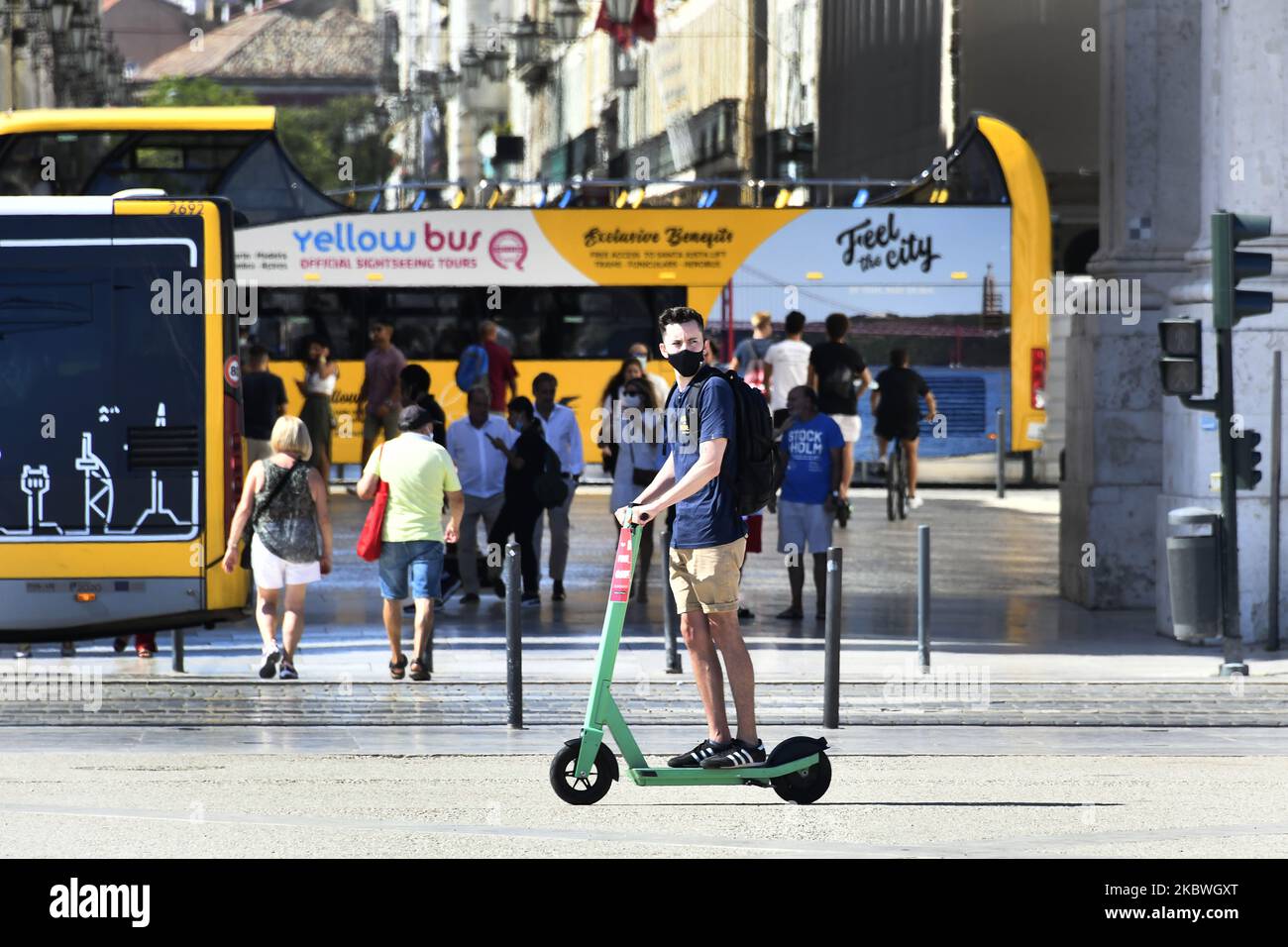 A man wearing protective masks ride scooter in Praça de Comércio, Lisbon. July 31th, 2020. Health Minister Marta Temido reported that there are 12,864 active cases of COVID-19 disease in Portugal, including outbreak-related infections. In total there are 194 active outbreaks in the country: 47 in the North region, 12 in the Centre, 106 in Lisbon and Tagus Valley, 14 in the Alentejo and 15 in the Algarve region. The outbreaks are considered active even if several days have passed since the last confirmed case. 'We only consider an outbreak to be extinct when 28 days (two incubation periods) hav Stock Photo