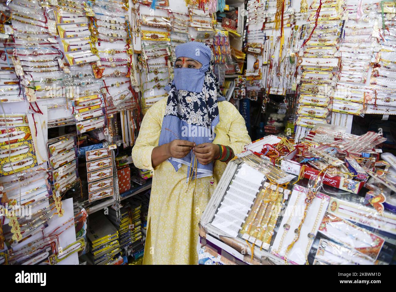Woman selling rakhi in a roadside stall wearing face protection mask in ...