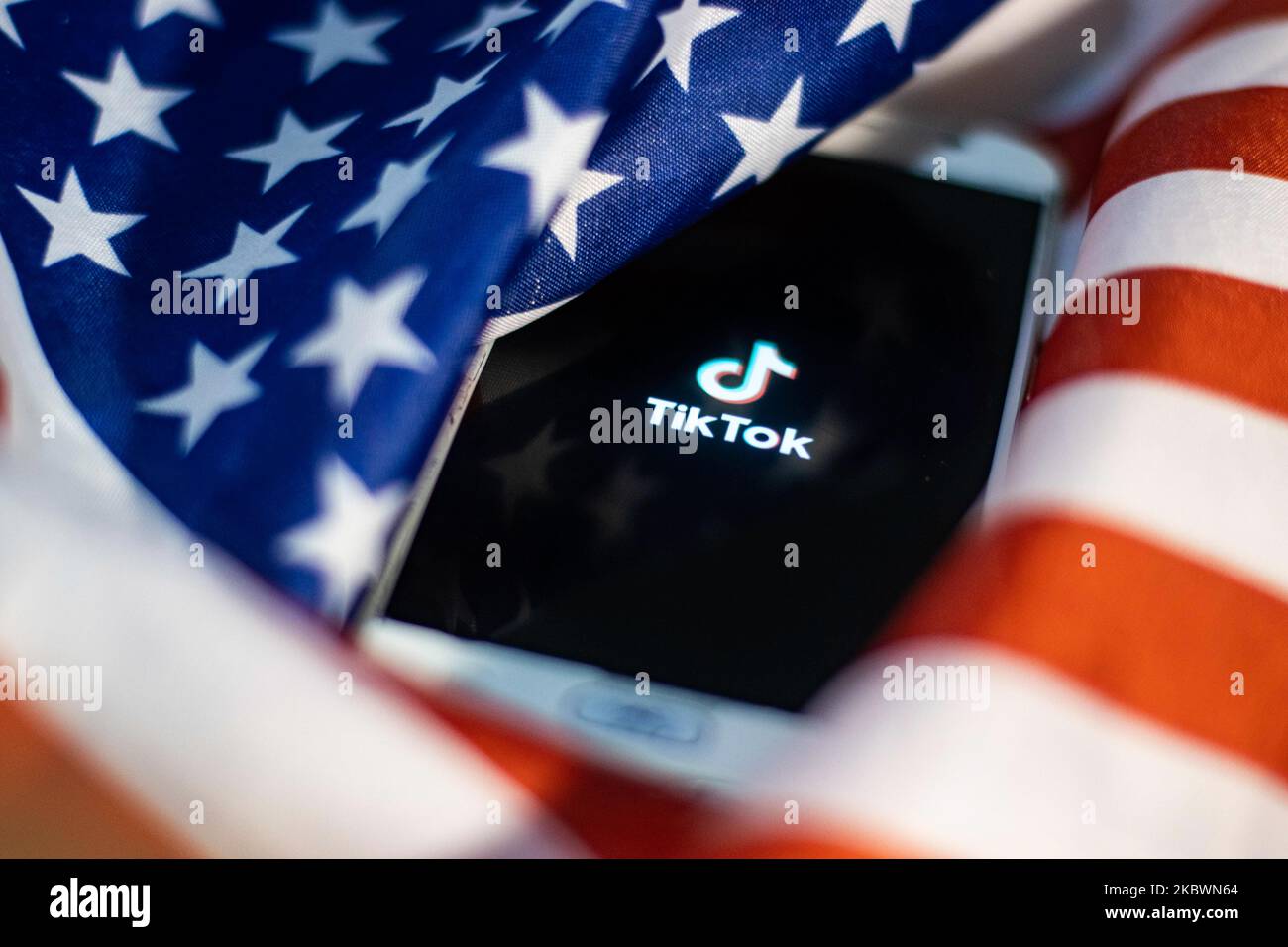 TikTok closeup logo displayed on a phone screen, smartphone on the American flag or U.S. flag, the national flag of the United States are seen in this multiple exposure illustration. Tik Tok is a Chinese video-sharing social networking service owned by a Beijing based internet technology company, ByteDance. It is used to create short dance, lip-sync, comedy and talent videos. ByteDance launched TikTok app for iOS and Android in 2017 and earlier in September 2016 Douyin fror the market in China. TikTok became the most downloaded app in the US in October 2018. President of the USA Donald Trump i Stock Photo