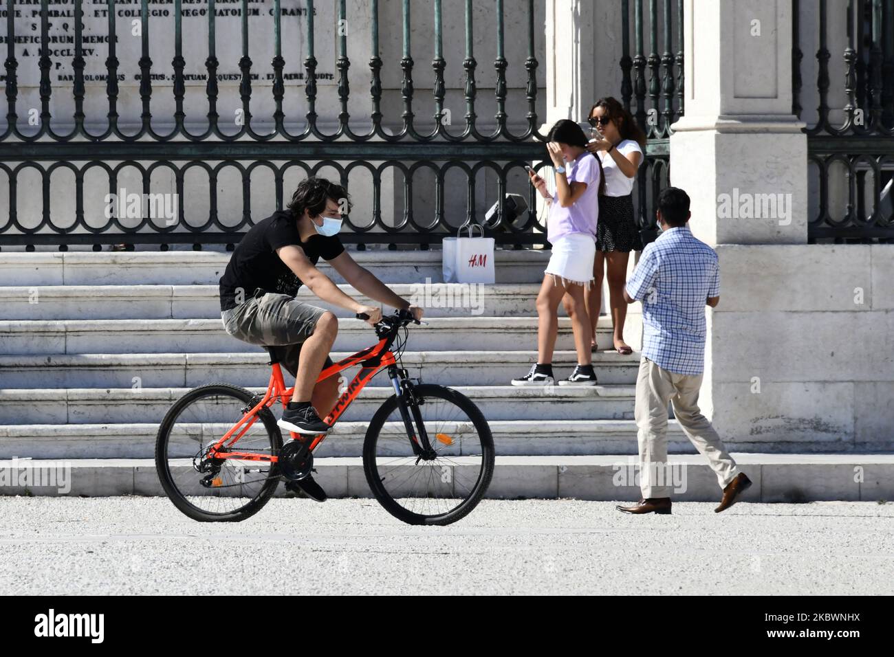 A man wearing a protective mask rides a bicycle in Praça de Comércio, Lisbon, Portugal on 4 August 2020. Portugal registered on Monday, August 3, its first day without deaths from COVID-19 since mid-March and at the same time reported the lowest number of new cases in almost three months. The absence of deaths was highlighted at a press conference as a 'positive note of hope' by the Secretary of State for Health, António Lacerda Sales. (Photo by Jorge Mantilla/NurPhoto) Stock Photo