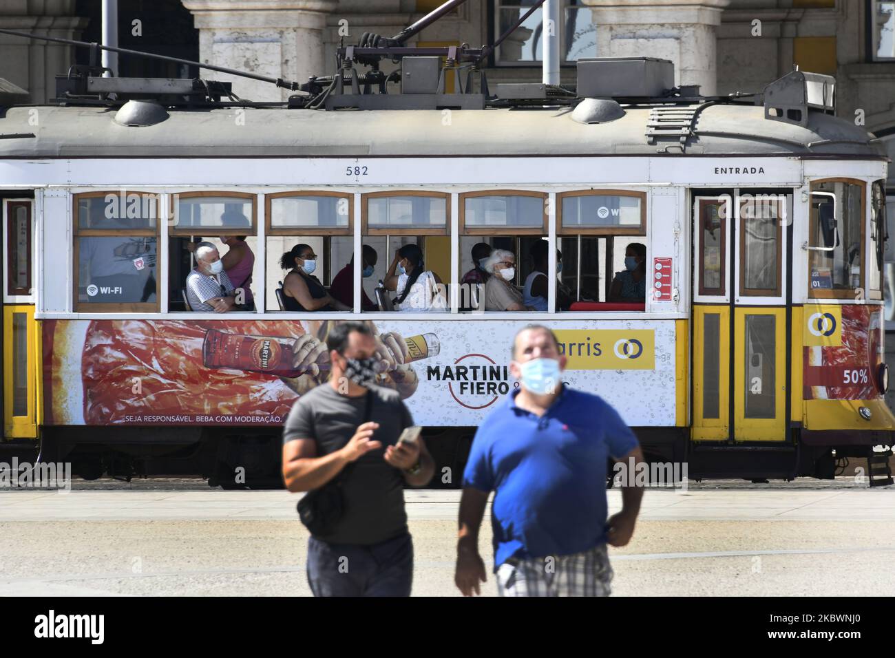 Two persons wearing protective masks walk near an electric train in Praça de Comércio, Lisbon, Portugal on 4 August 2020. Portugal registered on Monday, August 3, its first day without deaths from COVID-19 since mid-March and at the same time reported the lowest number of new cases in almost three months. The absence of deaths was highlighted at a press conference as a 'positive note of hope' by the Secretary of State for Health, António Lacerda Sales. (Photo by Jorge Mantilla/NurPhoto) Stock Photo