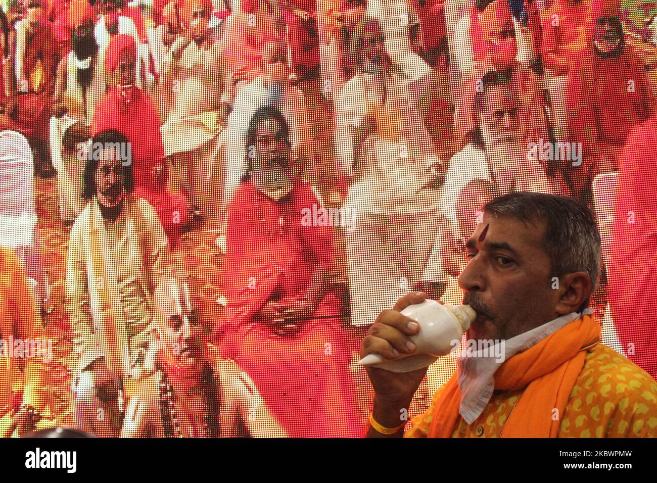 Temple priests celebrate by blowing a conch shell during a live telecast on a screen from Ayodhya of India's Prime Minister Narendra Modi participated in a ''Bhoomi Pujan'' or a groundbreaking ceremony to mark the building of a grand Ram temple, at Vivek Vihar in New Delhi on August 5, 2020. The Ayodhya dispute came to a conclusion last year with the ruling of Supreme Court when it asked the Union government to handover the site for the construction of Ram temple. The court also ordered to give an alternate five acres of land in another place to the Sunni Waqf Board for the purpose of building Stock Photo